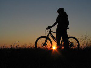girl stands with bicycle as sun sets girl stands with bicycle as sun sets